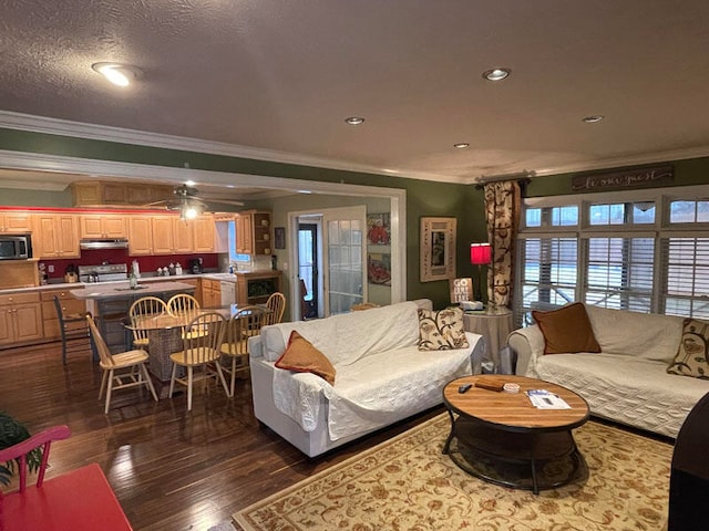 living room featuring dark hardwood / wood-style flooring, ceiling fan, ornamental molding, and a textured ceiling