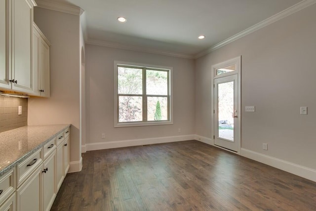 interior space with backsplash, dark hardwood / wood-style flooring, ornamental molding, and light stone countertops