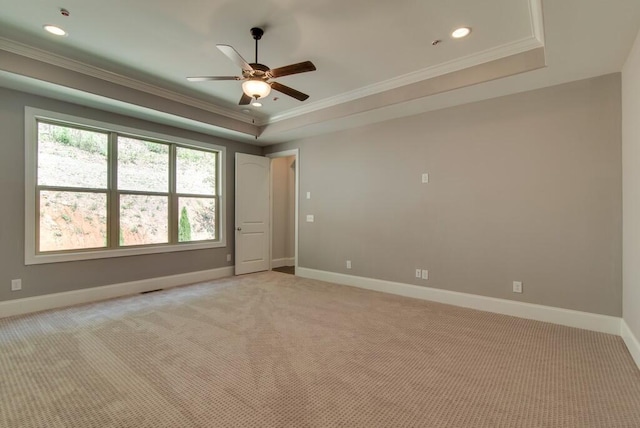 spare room featuring ceiling fan, ornamental molding, a tray ceiling, and light carpet