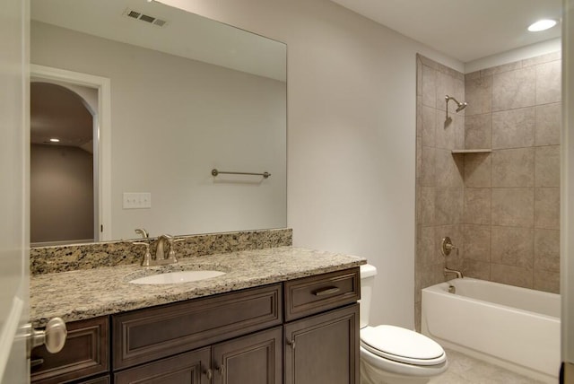 full bathroom with tiled shower / bath combo, vanity with extensive cabinet space, and toilet