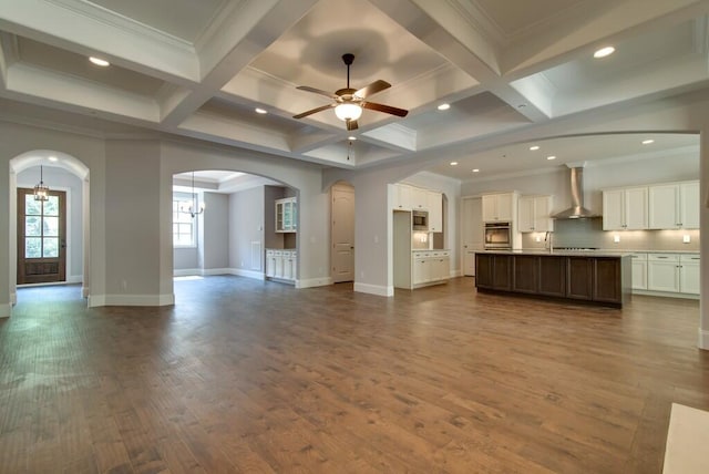 unfurnished living room with coffered ceiling, ceiling fan with notable chandelier, dark hardwood / wood-style flooring, and beamed ceiling