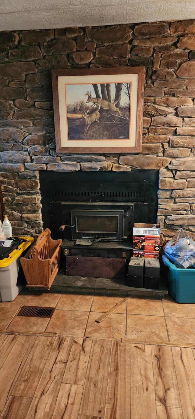 interior space with a textured ceiling, a fireplace, and a wood stove