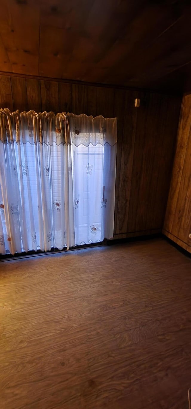 empty room featuring wooden walls, wooden ceiling, and dark hardwood / wood-style floors