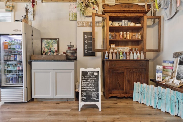 bar featuring light wood-style flooring and freestanding refrigerator