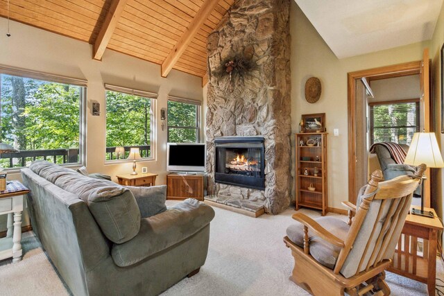 carpeted living room with beam ceiling, a stone fireplace, high vaulted ceiling, and wood ceiling