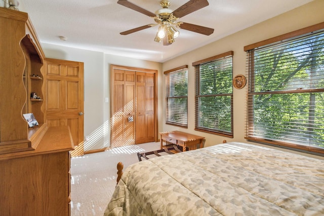 carpeted bedroom with a textured ceiling, a closet, and ceiling fan