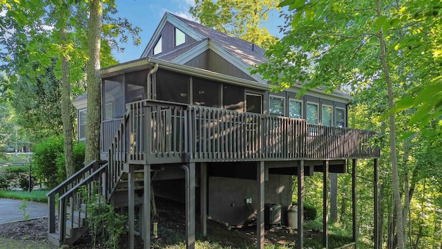 rear view of property featuring a deck, stairway, central AC unit, and a sunroom