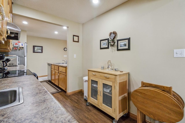 kitchen with a sink, light countertops, baseboards, dishwasher, and dark wood-style flooring