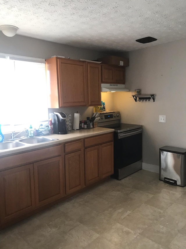 kitchen featuring a textured ceiling, range with electric stovetop, and sink