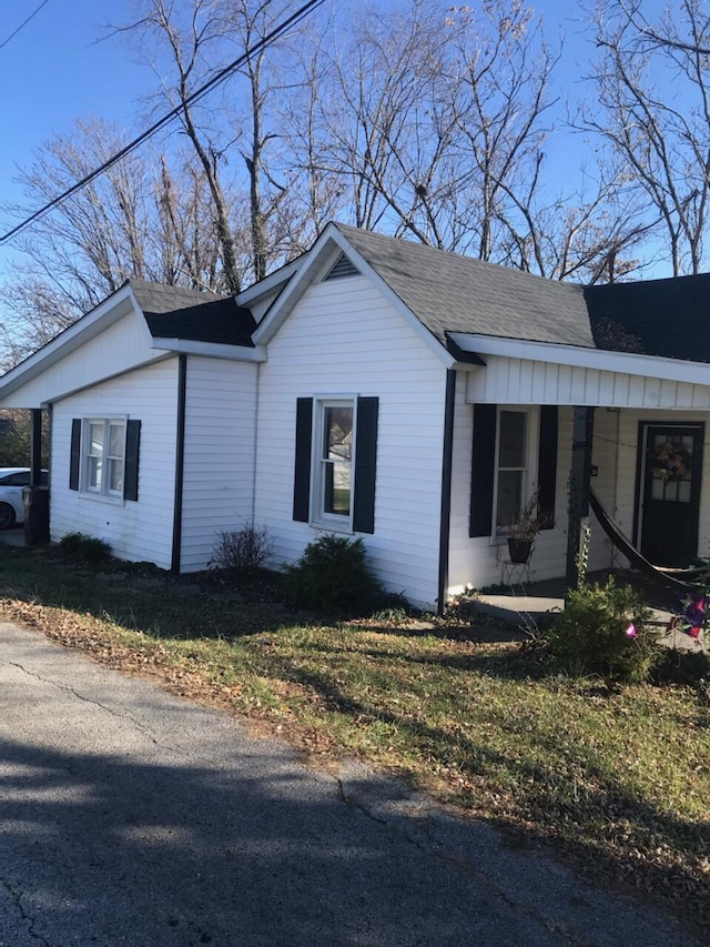 view of property exterior with covered porch and a yard