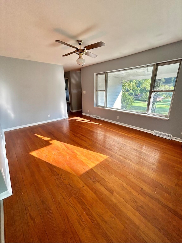 empty room with plenty of natural light, ceiling fan, and light wood-type flooring