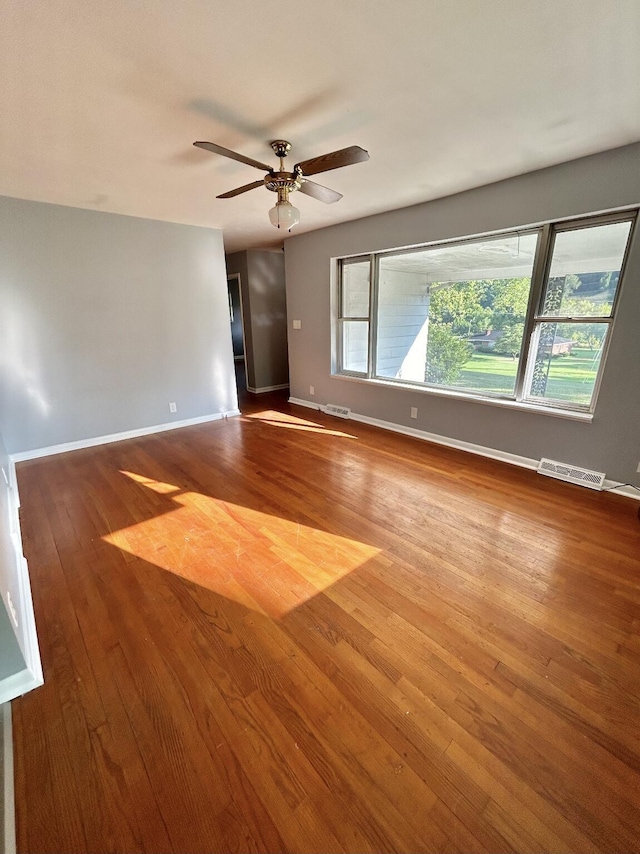 spare room with a wealth of natural light, ceiling fan, baseboards, and wood finished floors