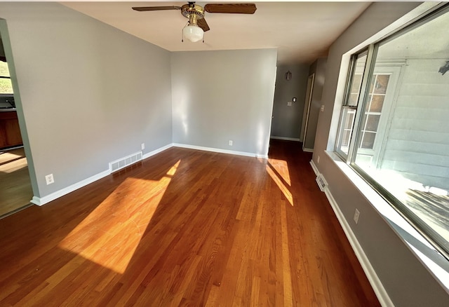 spare room with dark wood finished floors, visible vents, and baseboards