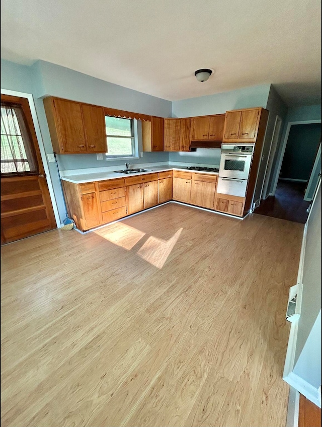 kitchen with sink, light hardwood / wood-style flooring, and oven