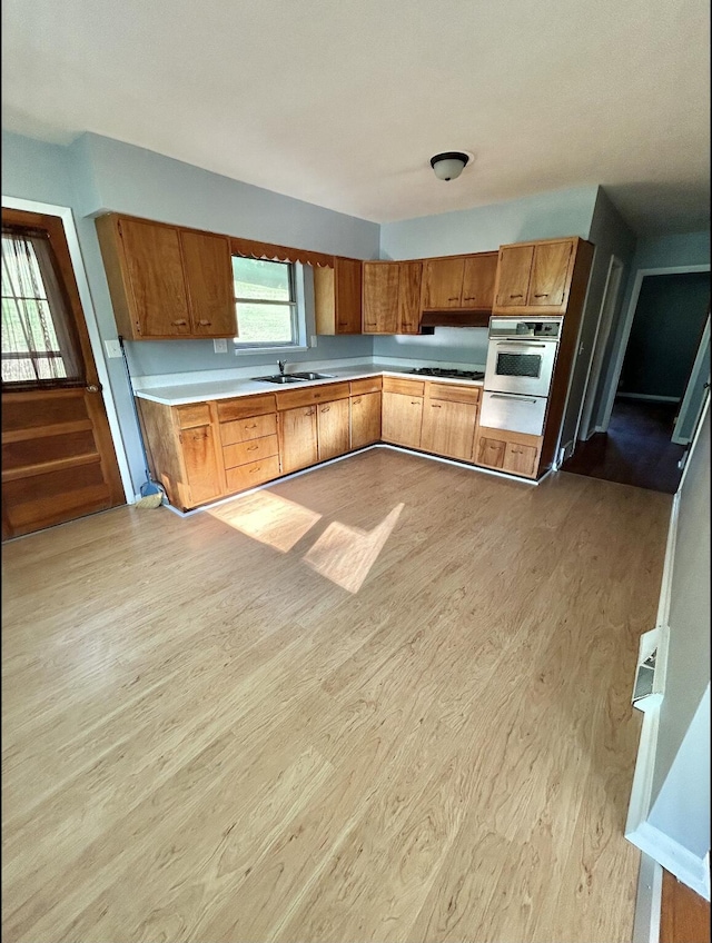 kitchen with brown cabinets, light wood-style flooring, light countertops, and oven