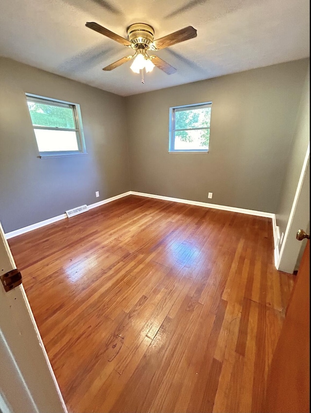 spare room with visible vents, ceiling fan, baseboards, and wood finished floors