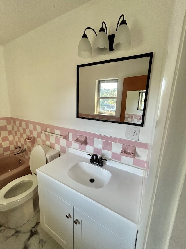 bathroom with toilet, a wainscoted wall, vanity, and tile walls