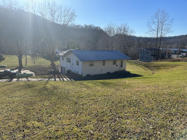 view of home's exterior with metal roof and a yard