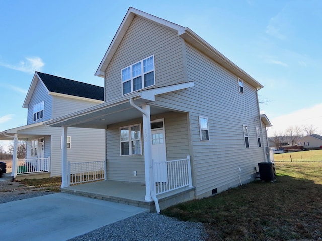 view of front of house featuring central AC, covered porch, and a front lawn