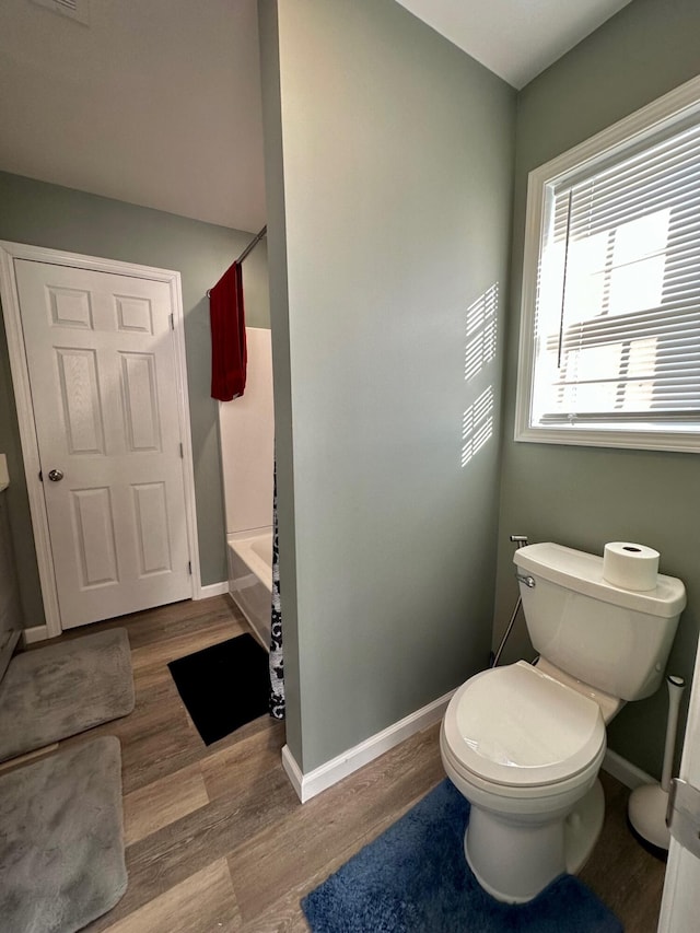 bathroom with toilet, hardwood / wood-style flooring, and shower / bath combination