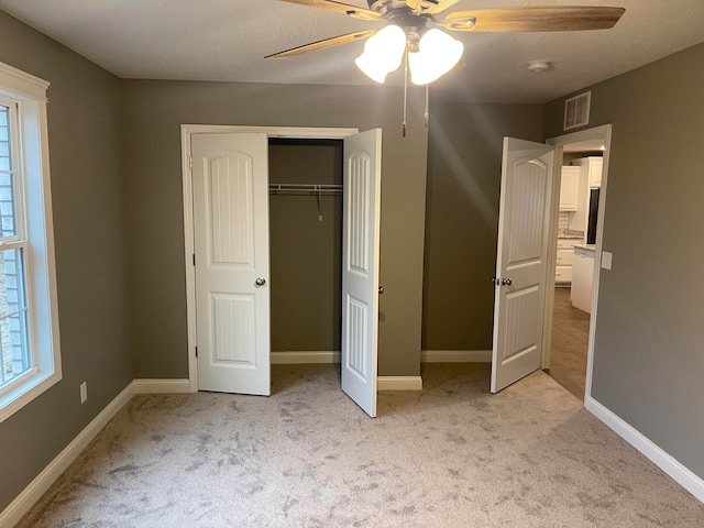 unfurnished bedroom featuring a closet, ceiling fan, and light colored carpet