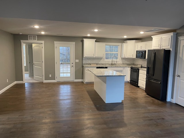 kitchen with white cabinetry, dark hardwood / wood-style floors, black appliances, and a wealth of natural light