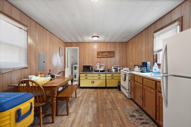 kitchen featuring wooden walls, light hardwood / wood-style flooring, white appliances, water heater, and electric panel