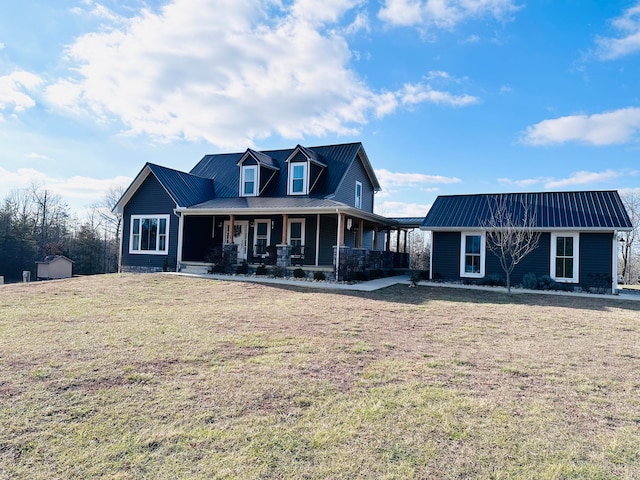 view of front facade with a porch, a front lawn, and an outbuilding