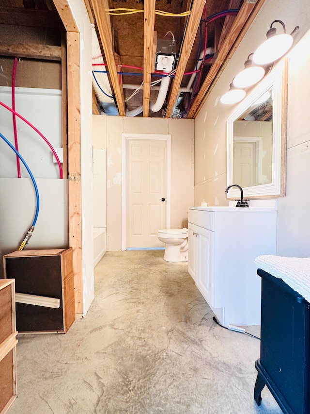 bathroom with toilet, concrete floors, and vanity