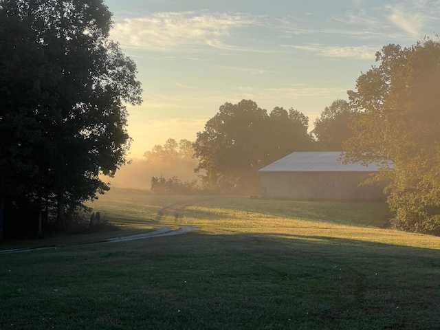 yard at dusk featuring a rural view