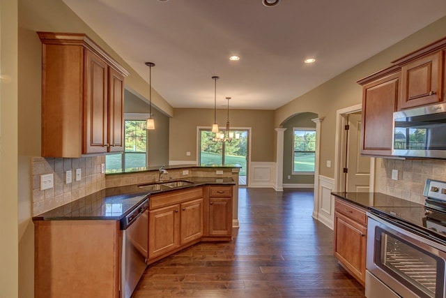 kitchen with decorative backsplash, sink, dark hardwood / wood-style flooring, hanging light fixtures, and appliances with stainless steel finishes