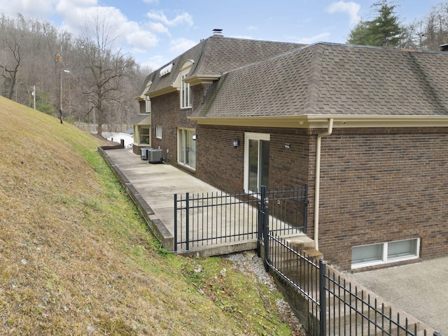 view of property exterior with central AC unit, a patio, and a yard