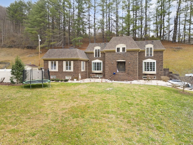 view of front facade with a patio, a trampoline, and a front lawn