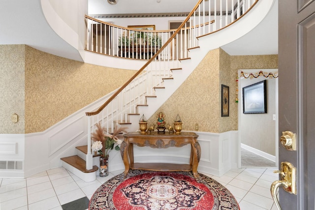 stairway with light tile floors and a towering ceiling