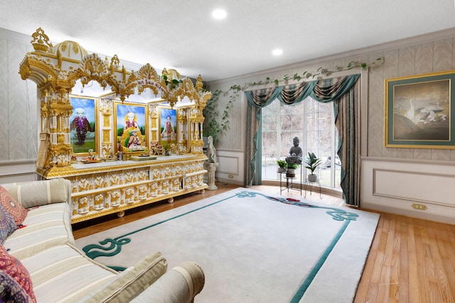 living room featuring ornamental molding, a textured ceiling, and light hardwood / wood-style flooring