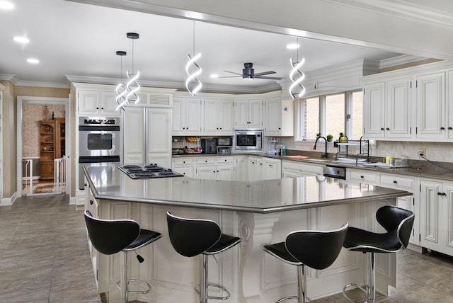 kitchen featuring ceiling fan, built in appliances, white cabinetry, and a breakfast bar area