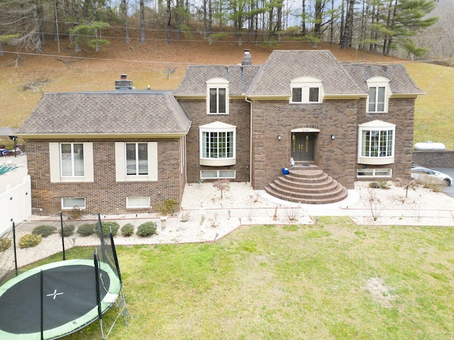 rear view of house with a trampoline and a lawn