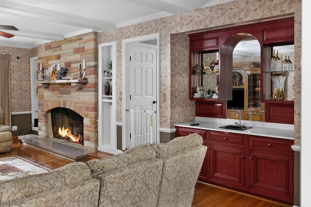 living room with a fireplace, dark wood-type flooring, ornamental molding, and ceiling fan