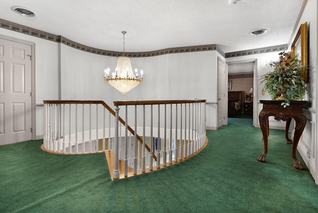 hallway featuring a notable chandelier, a textured ceiling, dark carpet, and ornamental molding