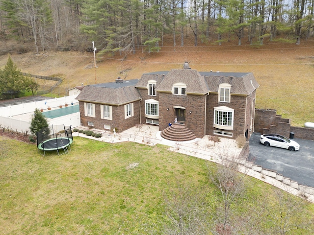 view of front of property featuring a trampoline and a front yard