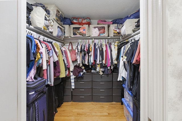 walk in closet with light hardwood / wood-style flooring