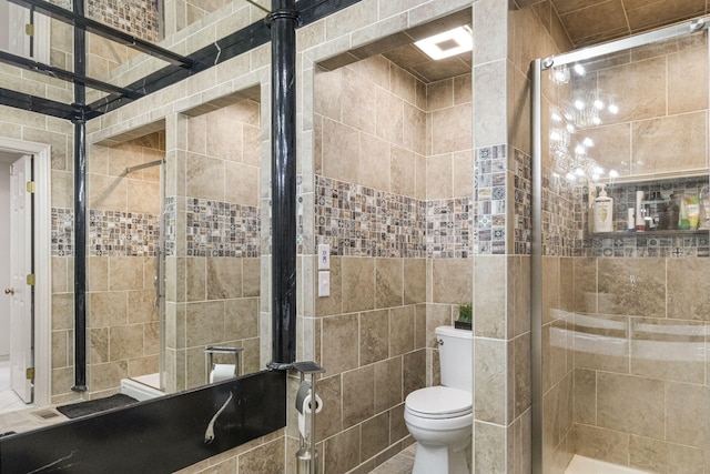 bathroom with a shower with shower door, tile walls, tile flooring, and toilet