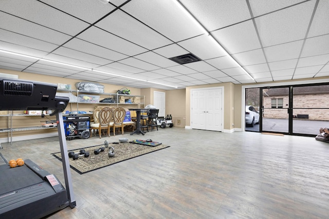 workout room with a paneled ceiling and light hardwood / wood-style flooring