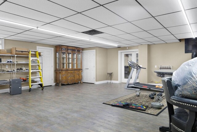 exercise room with a paneled ceiling and dark hardwood / wood-style floors