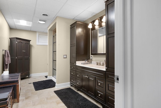 bathroom with tile floors, vanity, a shower with shower door, and a paneled ceiling