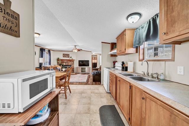 kitchen with ceiling fan, white appliances, a fireplace, a textured ceiling, and sink