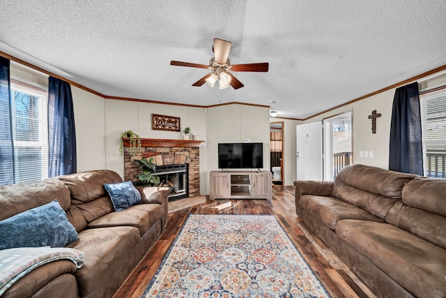 living room featuring ceiling fan, ornamental molding, dark hardwood / wood-style flooring, a fireplace, and a textured ceiling