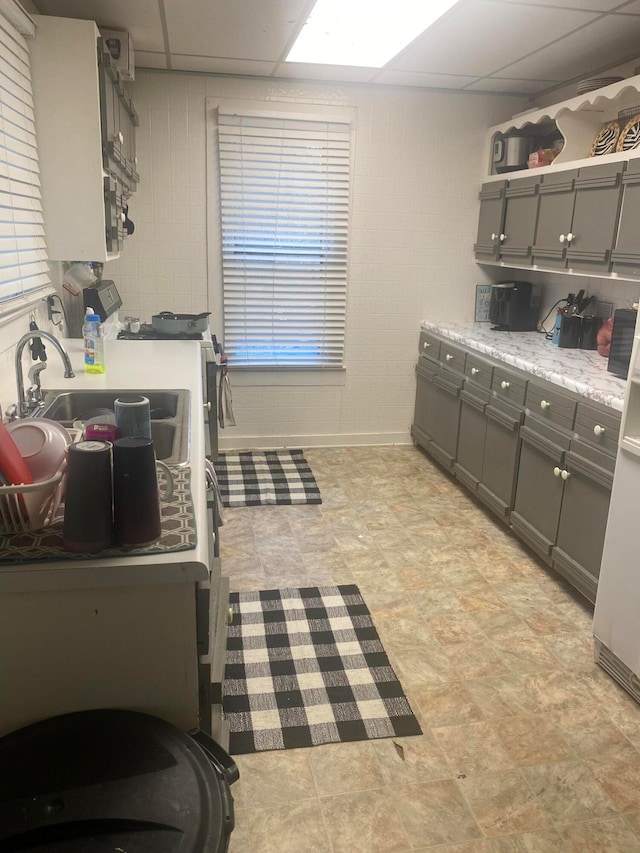 kitchen with a paneled ceiling, light tile floors, and gray cabinetry