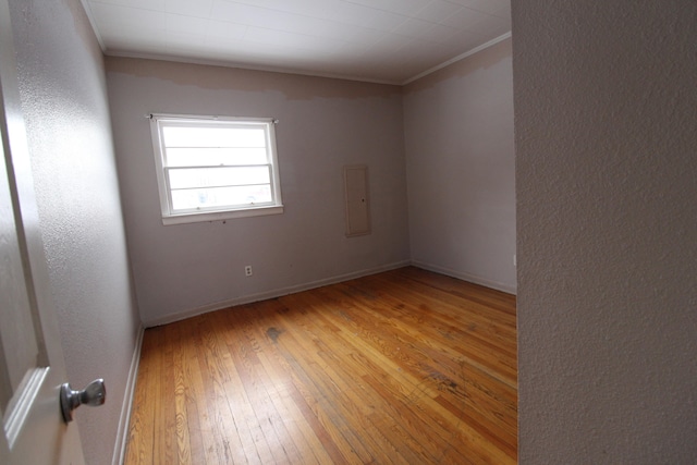 spare room with ornamental molding and light hardwood / wood-style floors