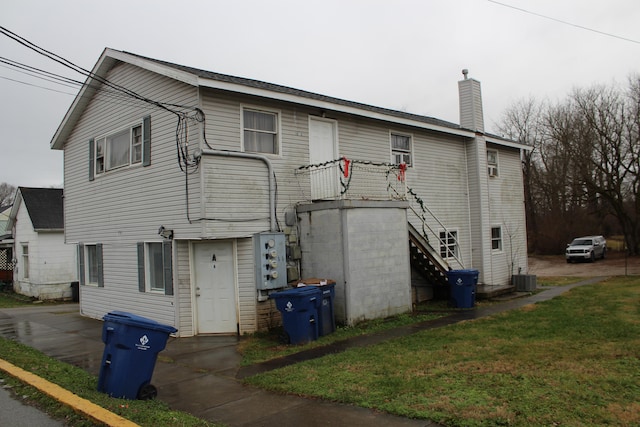 rear view of property featuring a yard and central AC unit